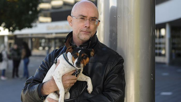 Stefan Svallfors står på ett torg med hund famnen