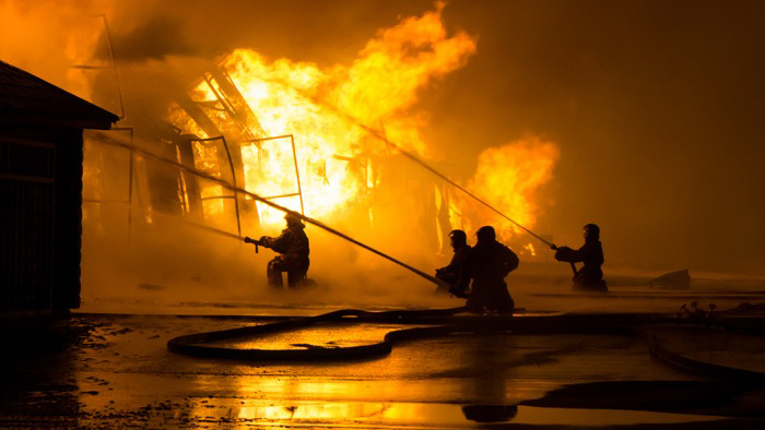 Brandsoldater sprutar eld på ett brinnande hus i natten.