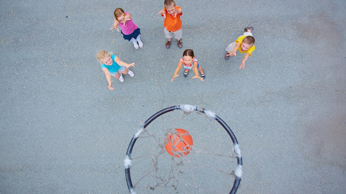 Fem barn som spelar basket.