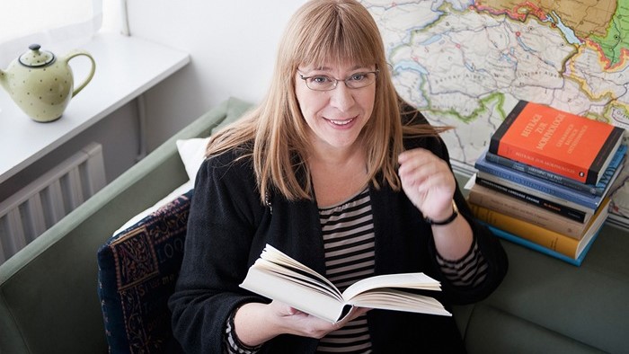 Professor Jenny Larsson sittandes med bok i hand.