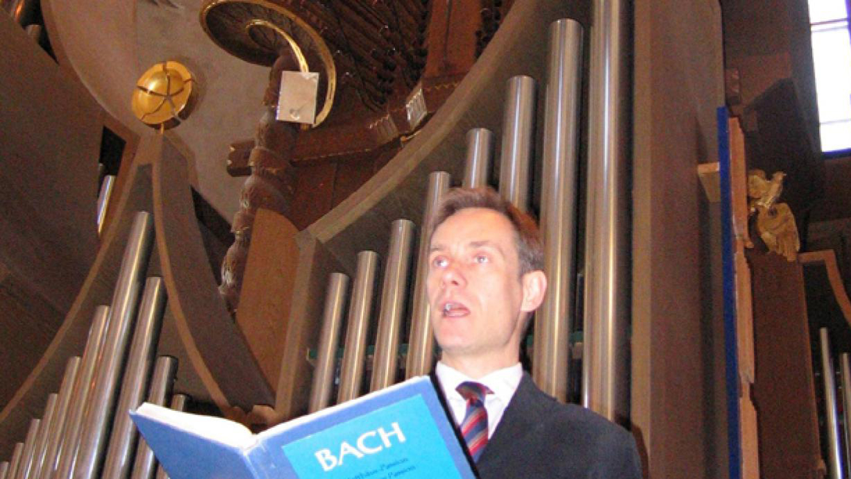 Carl Unander-Scharin står framför orgel.