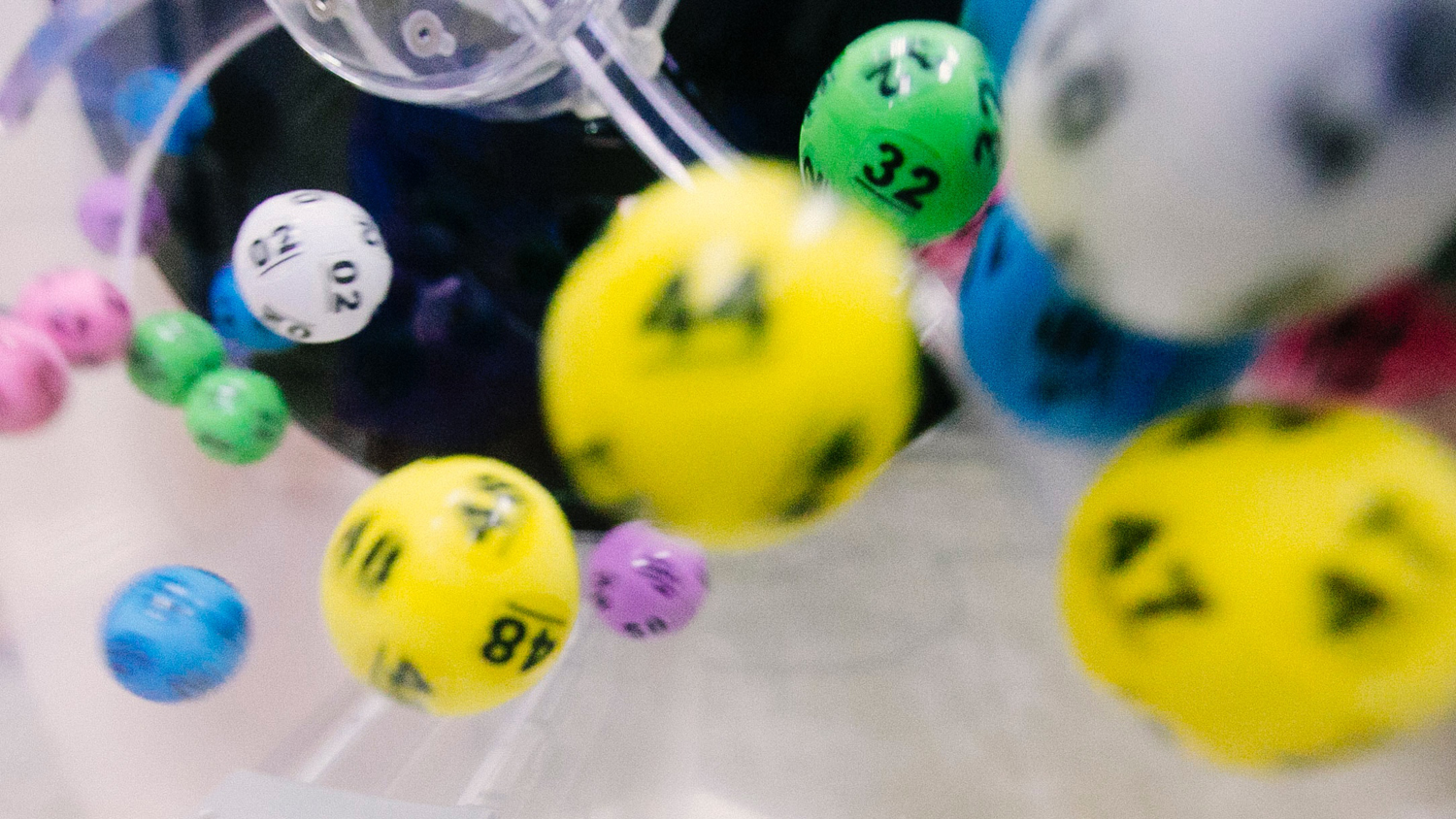 Lotteribollar med olika siffror och färger snurrar i en tombola.