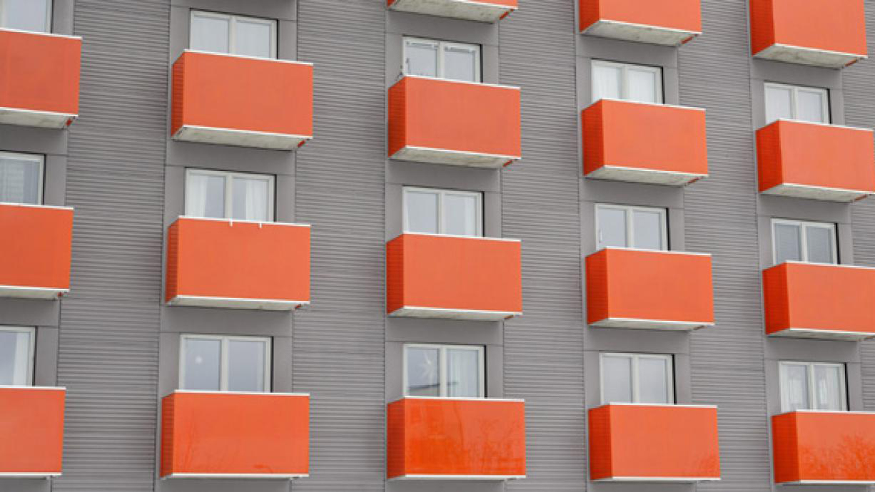  Byggnad med grå fasad och orange balkonger.