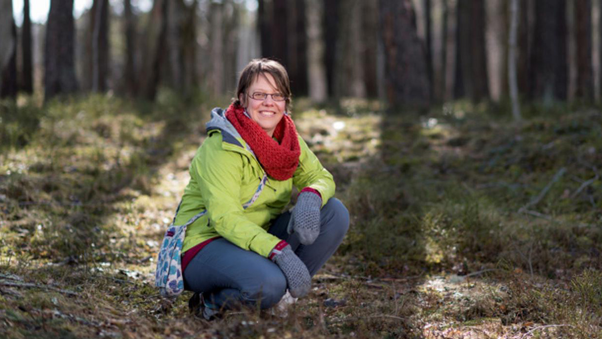 Anna Rosling sitter på huk i skogsmiljö.