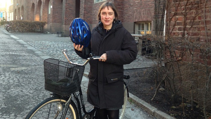 Nina Wormbs står vid sin cykel med cykelhjälm i handen.