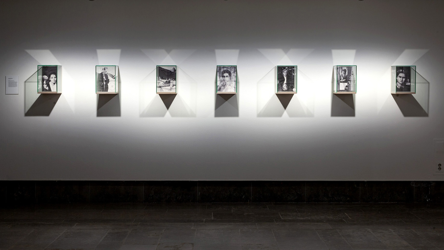 Utställning med sju porträttbilder  i  ramar som är som kuber.