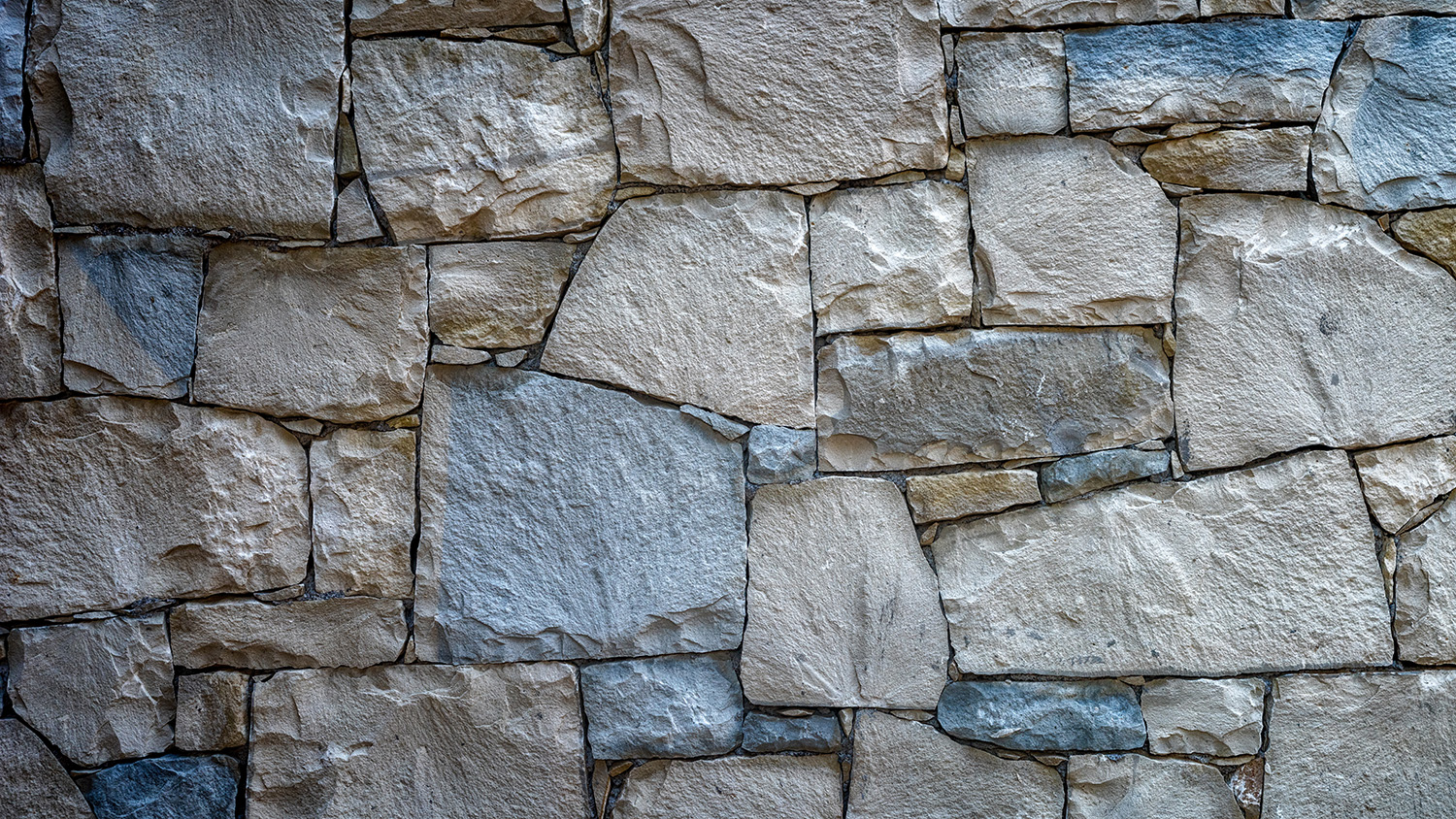 Murad vägg med stenblock i olika storlekar i blått och grått.