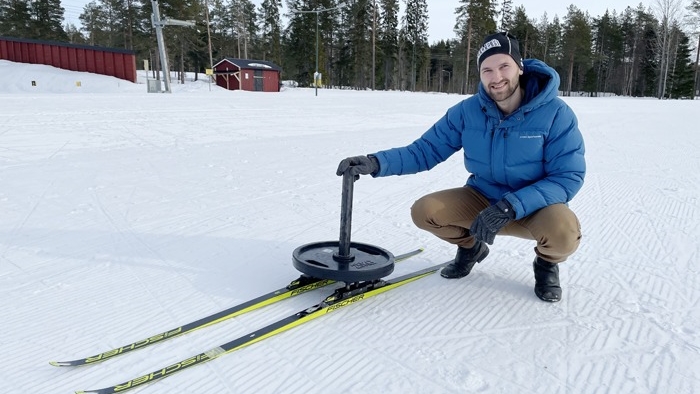 Kalle Kalliorinne sitter på huk bredvid ett par skidor