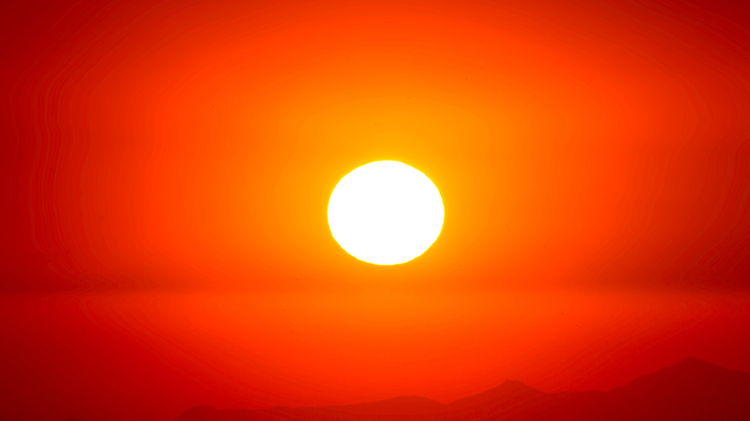 Stark sol på röd och orange himmel med horisont i nederkant