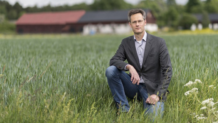 Fredrik Thiesner står på knä i lantbruksmiljö.