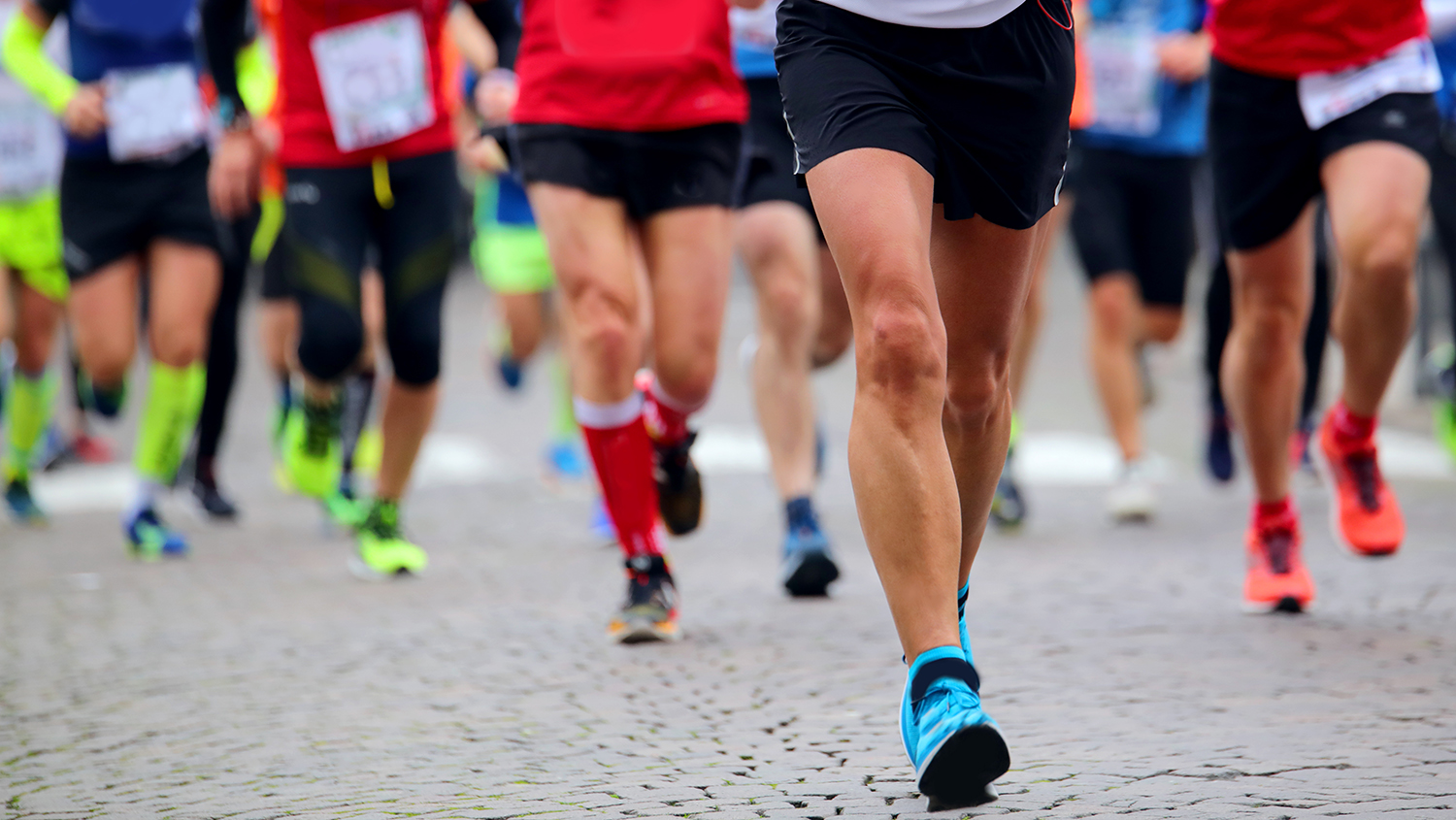 Många springande ben i shorts och gympaskor på en gata